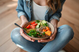 Girl holds a plate with healthy food sitting on the floor. Healthy eating concept. Take away food to home.