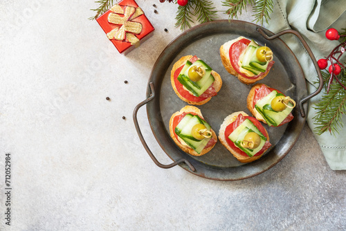Creative appetizers christmas. Christmas tree canapes of salami, cheese, olives, tomatoes and cucumbers on a baguette. View from above. Copy space.