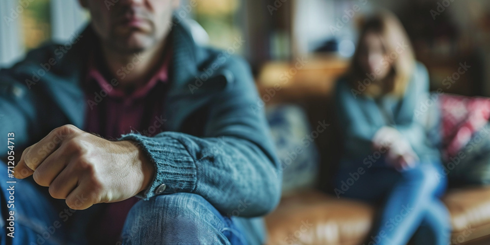 Anger abuse and domestic violence concept. Man threatening wife and kids with his fist. Scared mother and child sitting together on couch in scare. Selective Focus on male hand Anger abuse and domestic violence concept. Man threatening wife and kids with his fist. Scared mother and child sitting together on couch in scare. Selective Focus on male hand