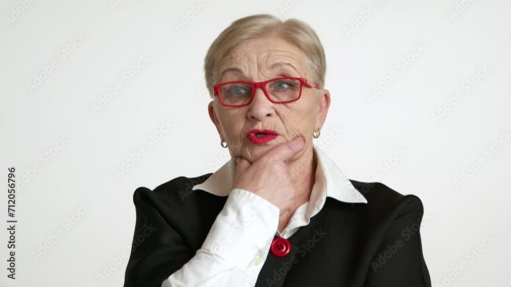 Confused blonde short-haired woman of 60-70 years with pleasant appearance in red eyeglasses, red lipstick looking for a solution to the problem, at loss. High quality 4k footage Confused blonde short-haired woman of 60-70 years with pleasant appearance in red eyeglasses, red lipstick looking for a solution to the problem, at loss. High quality 4k footage