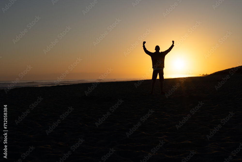 In silhouette one unrecognizable person at sunrise on beach