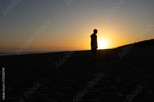 In silhouette one unrecognizable person at sunrise on beach