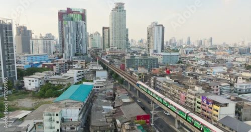 Drone tracking Bangkok Skytrain metro revealing skyscraper skyline in sunlight photo