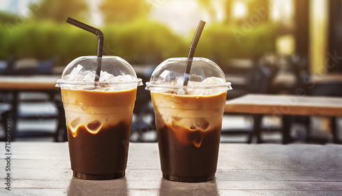 Plastic takeaway cups of delicious iced coffee on table in outdoor cafe with blurry background photo