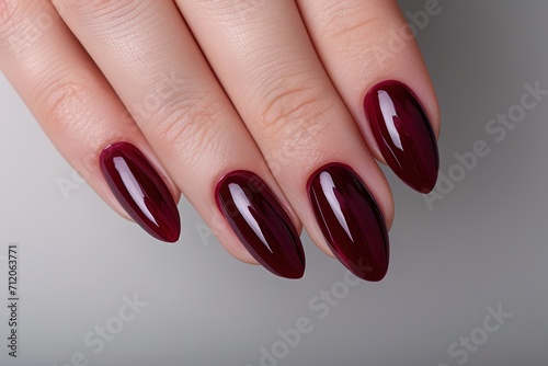 Woman hand with burgundy color nail polish on her fingernails. 