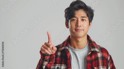 Asian man, pointing finger up at copy space isolated on background.