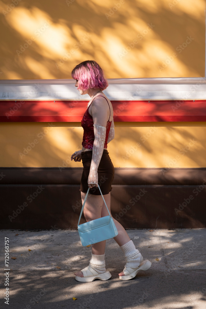 fashion young creative girl , pink colored hair, walking at street alone, light and shadows