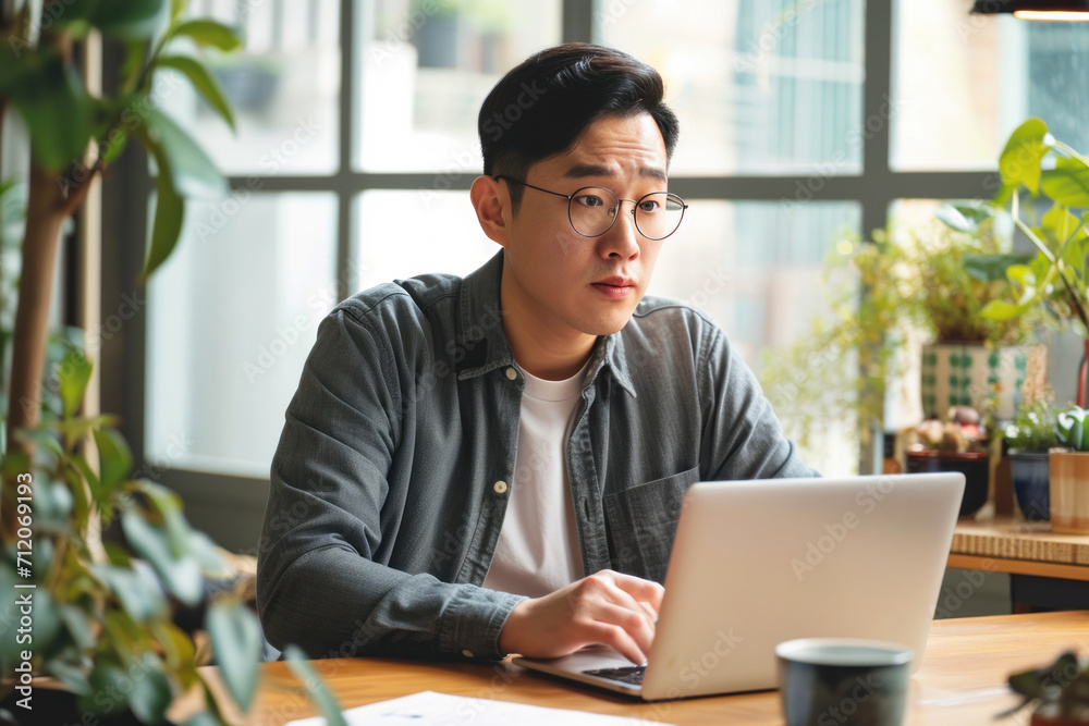 Asian freelance man sitting and working with laptop Showing a confused and troubled expression sit at the table with computer macbook Asian freelance man sitting and working with laptop Showing a confused and troubled expression sit at the table with computer macbook