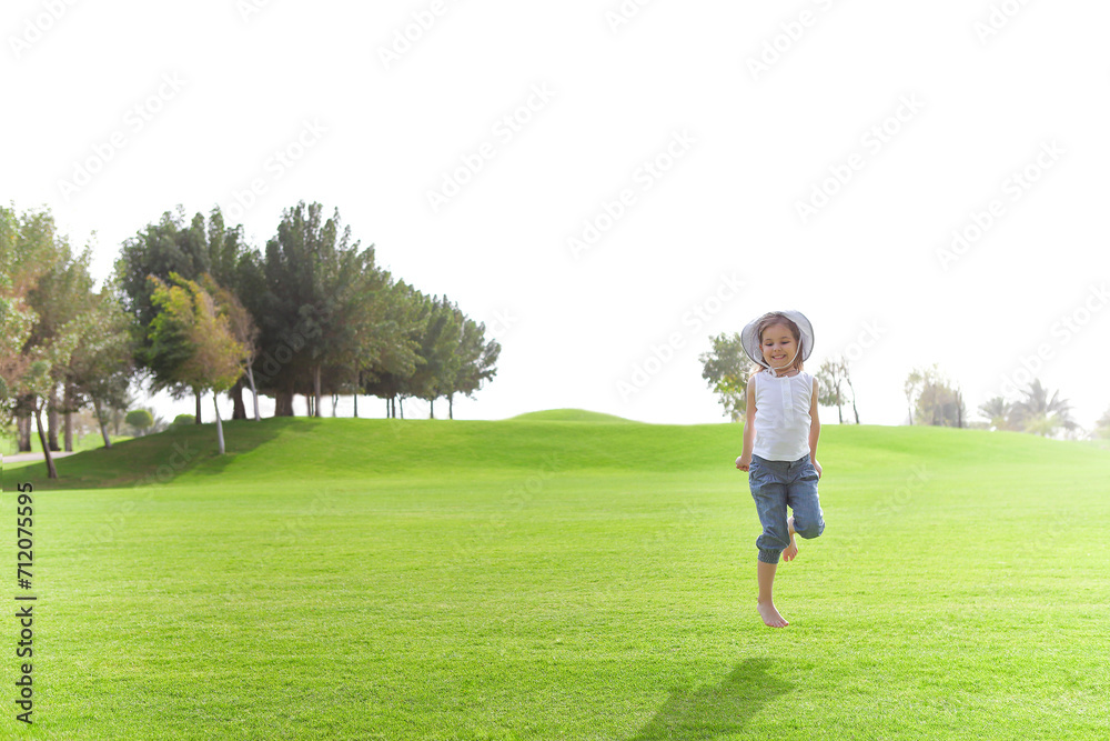 Playful girl on green lawn in summer