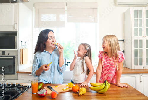 Beautiful little girls with they mother in the kitchen preparing a fruit salad