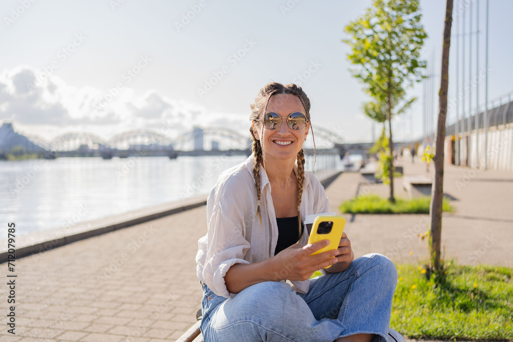 Fototapeta premium Young woman hipster sitting at city street , use cellophane, chatting with friends, have video call