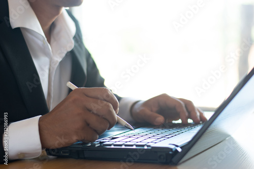 Businessman or accountant working on computer and taking notes on business documents on office table