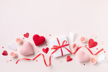 Valentine or mother day festive composition with gift or present box, rose flowers and red pink hearts on pastel background top view. Beautiful flat lay greeting card..