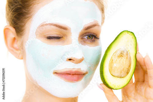 Girl facial mud mask holds avocado fruit