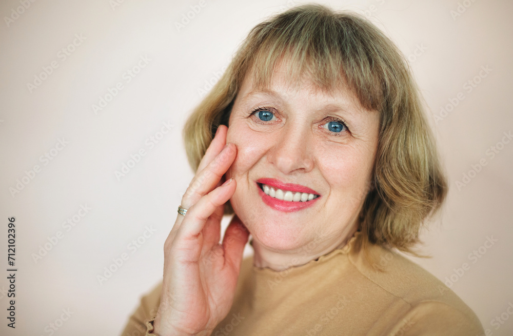 Smiling mature woman touching face in studio Smiling mature woman touching face in studio