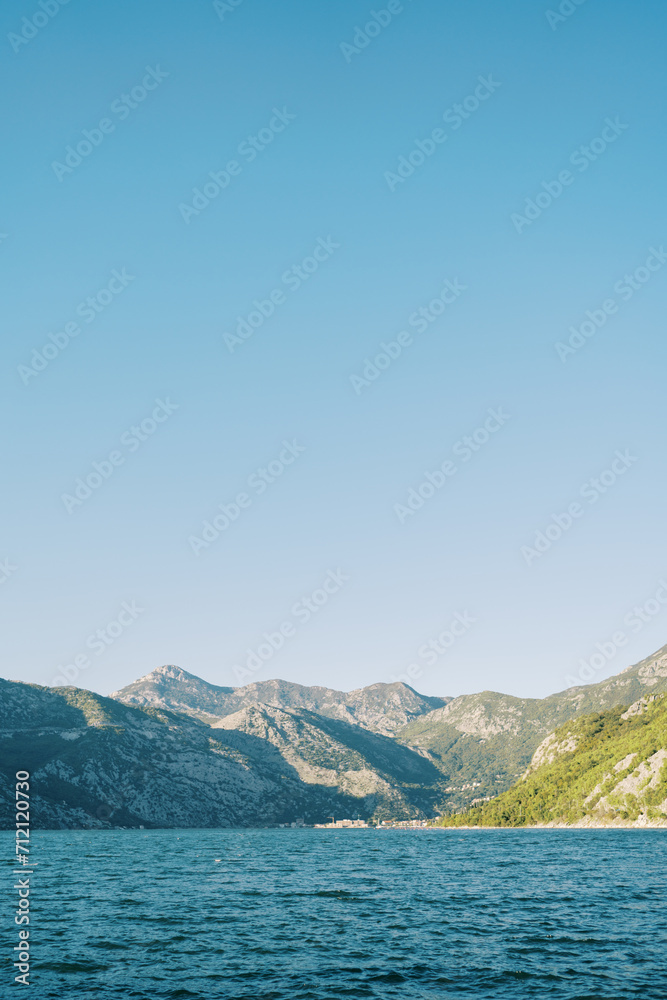 View from the Bay of Kotor to a high mountain range against a blue sky. Montenegro