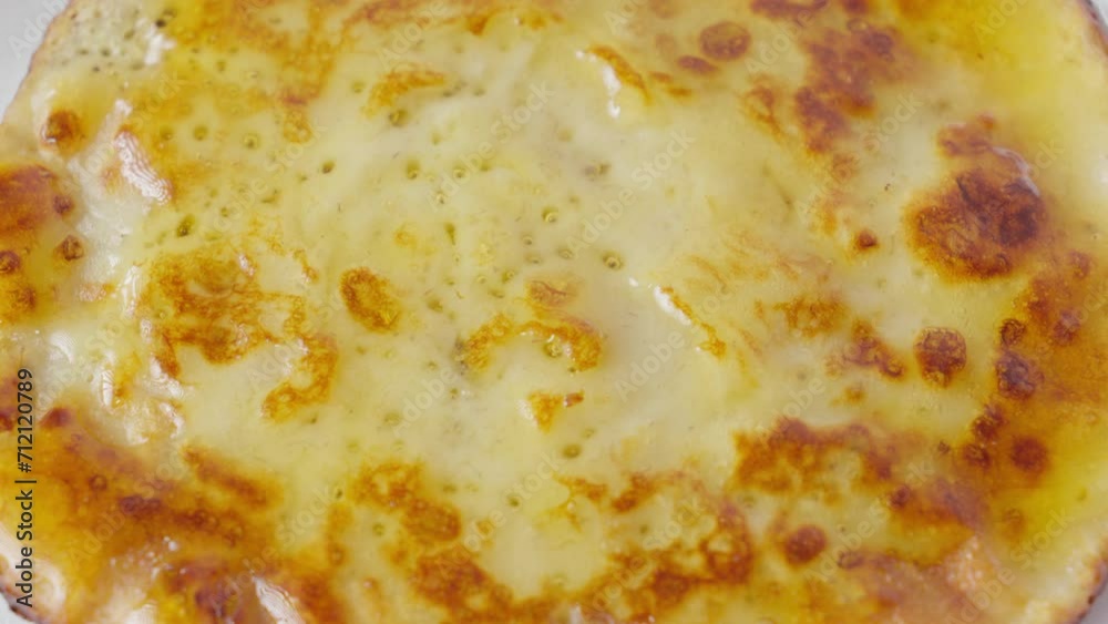 Close up of a spoon spreading jam on a freshly cooked tempting pancake Close up of a spoon spreading jam on a freshly cooked tempting pancake