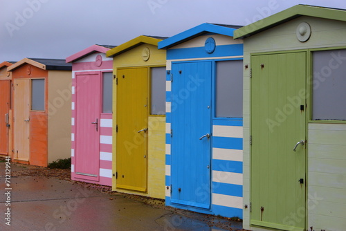 Colorful beach huts at the beach. Rainbow coloured beach huts along the walkway, closed on a rainy, overcast summer day in England. Beach closed concept, rain on my parade idea - Seaford Beach, Sussex