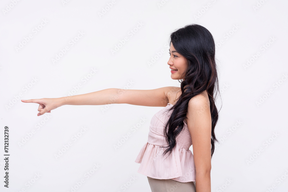 Cheerful young woman with long hair smiling and pointing to the side, isolated on a white background. Cheerful young woman with long hair smiling and pointing to the side, isolated on a white background.