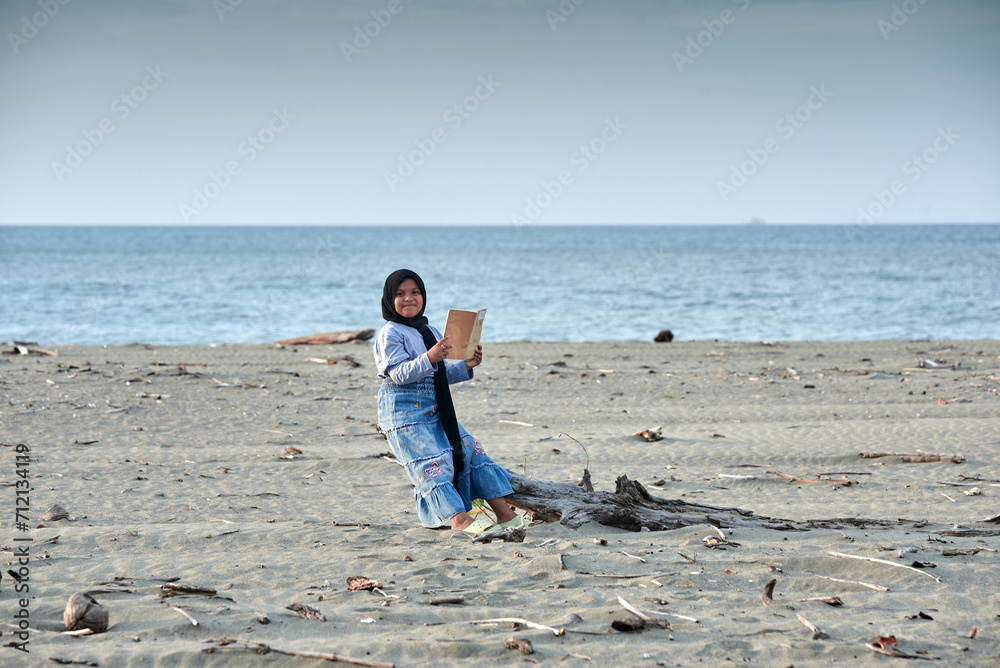 Little Girl reading a book on the tropical beach