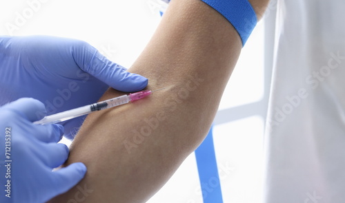 Close-up of nurse injects medication in womans vein with needle  blood test in hospital. Qualified medical worker hold needle. Medicine  health concept