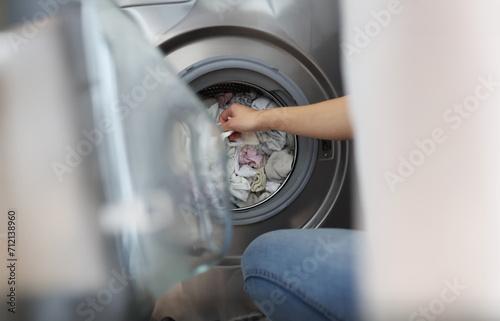 Close-up of woman loading washing machine with dirty clothes, taking out clean stuff. Household, bathroom, domestic chores, cleaning day, housewife concept