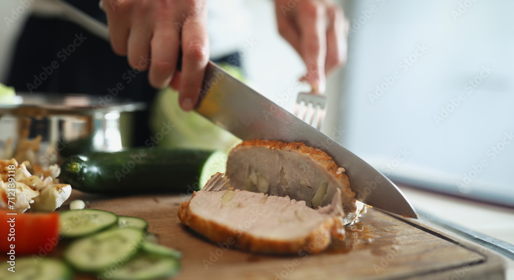 Close-up of person cutting homemade ham, delicious aromatic meat with garlic pieces. Housewife preparing meat for dinner. Chef, food, eating, yum concept