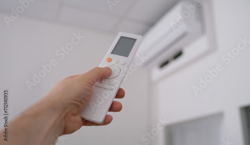 Person is holding air conditioner remote control. Climate control in the house concept