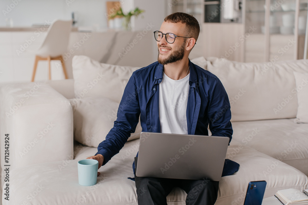 Smiling man with laptop and coffee mug on a comfortable couch Smiling man with laptop and coffee mug on a comfortable couch