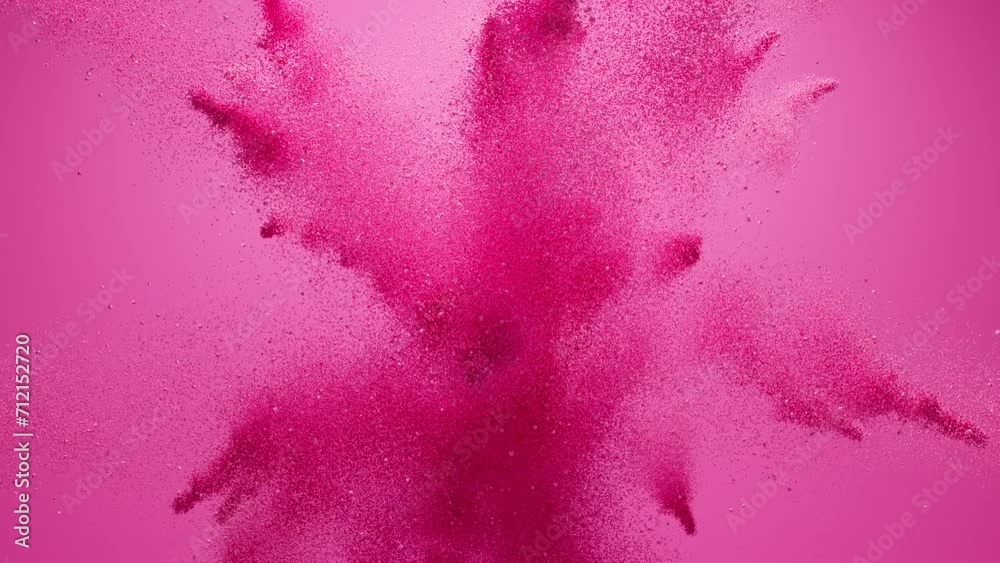 Pink dust explosion on pink background. Vibrant particles burst and move in slow motion.  