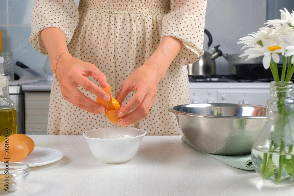 Woman separates yolk and white over bowl on kitchen preparing food at home, close-up view. Cooking protein dish, pastry, baking with eggs. Cuisine, cook meal on kitchen. Fresh organic ingredients. Woman separates yolk and white over bowl on kitchen preparing food at home, close-up view. Cooking protein dish, pastry, baking with eggs. Cuisine, cook meal on kitchen. Fresh organic ingredients.
