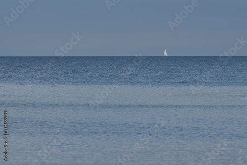 a sailing yacht sails on the horizon at sea