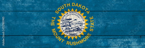 South Dakota State flag on a wooden surface. Banner of the grunge South Dakota State flag.