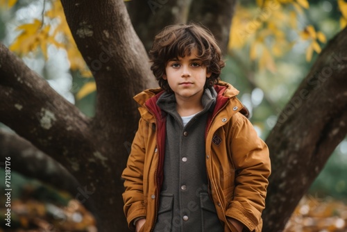 Portrait of a boy in a yellow coat on a background of autumn trees.
