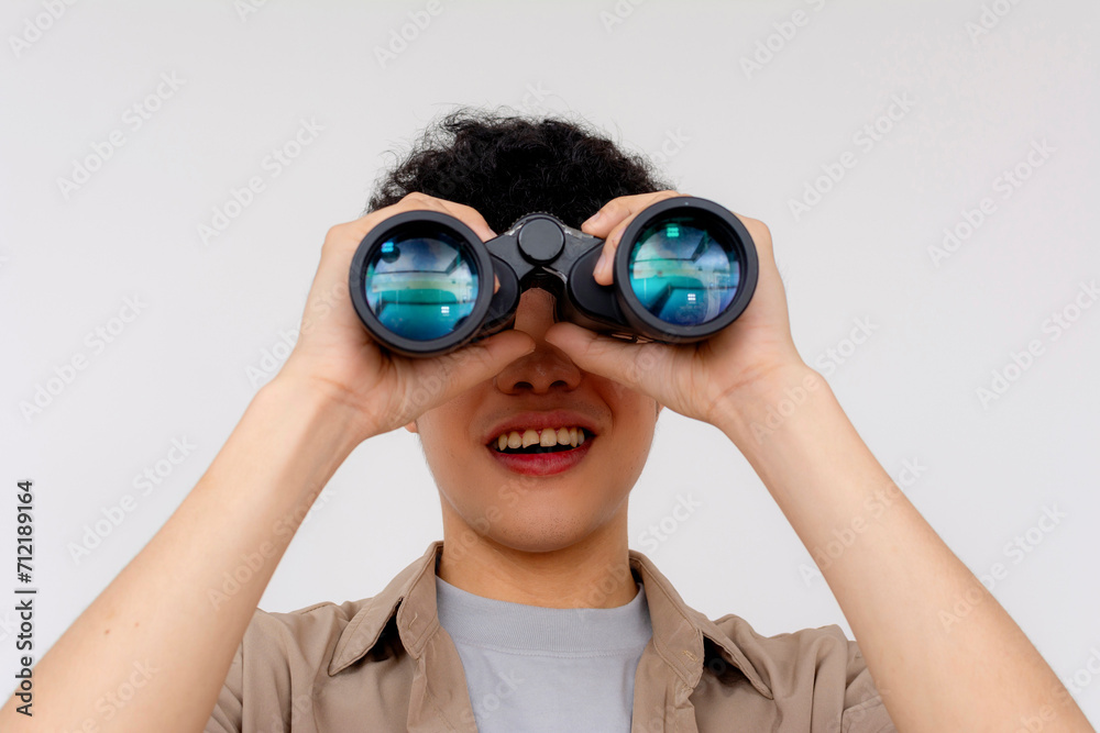 A cheerful young Asian man is using binoculars to explore, symbolizing curiosity, search, and discovery. A cheerful young Asian man is using binoculars to explore, symbolizing curiosity, search, and discovery.