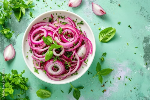 Healthy fermented food Top down view of pickled red onion rings fresh herbs white bowl Green background photo