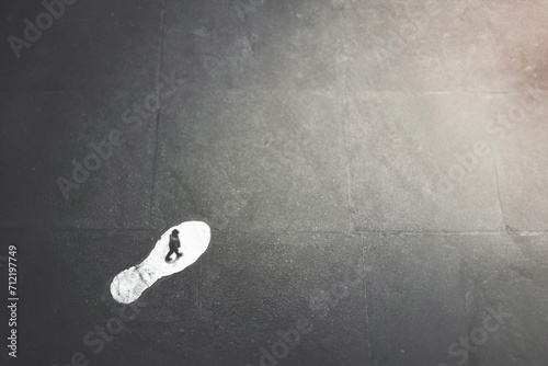 Foto man follows the path of a surreal giant footprint on the.  street