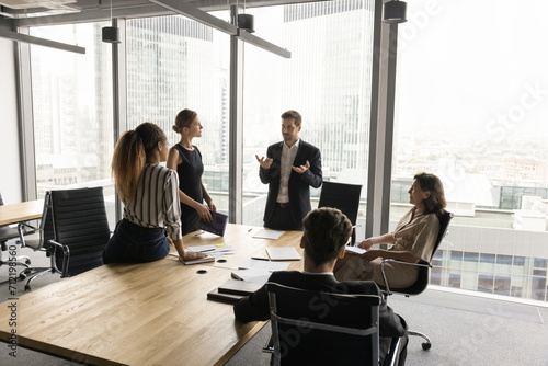 Diverse group of business partners discussing investment for startup on corporate meeting, talking on teamwork plan, marketing strategy. Team leader talking to managers in modern conference room photo