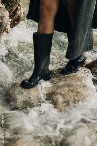 Girl in rubber boots on the rocks by the sea.