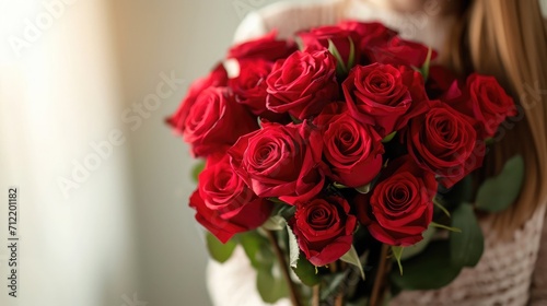 Woman holding luxury bouquet of fresh red roses on light background  closeup
