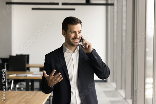 Successful positive manager discussing work project on mobile phone, enjoying telephone call from office, speaking on cell, smiling, laughing, using cellphone for business communication