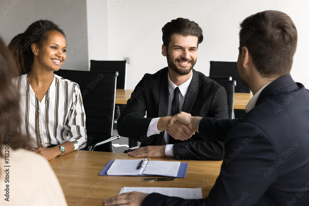 Company owner and project manager shaking hands over meeting table, smiling, discussing project success, investment, teamwork, successful partnership, working on cooperation, agreement Company owner and project manager shaking hands over meeting table, smiling, discussing project success, investment, teamwork, successful partnership, working on cooperation, agreement