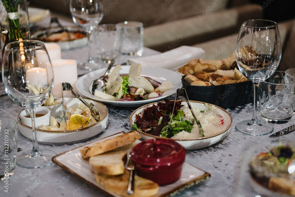 Food and drink on the dining table. Plate and glass. Wedding set up, dinner table reception in a restaurant. Serving, setting table in the hall. Birthday, baptism, event.