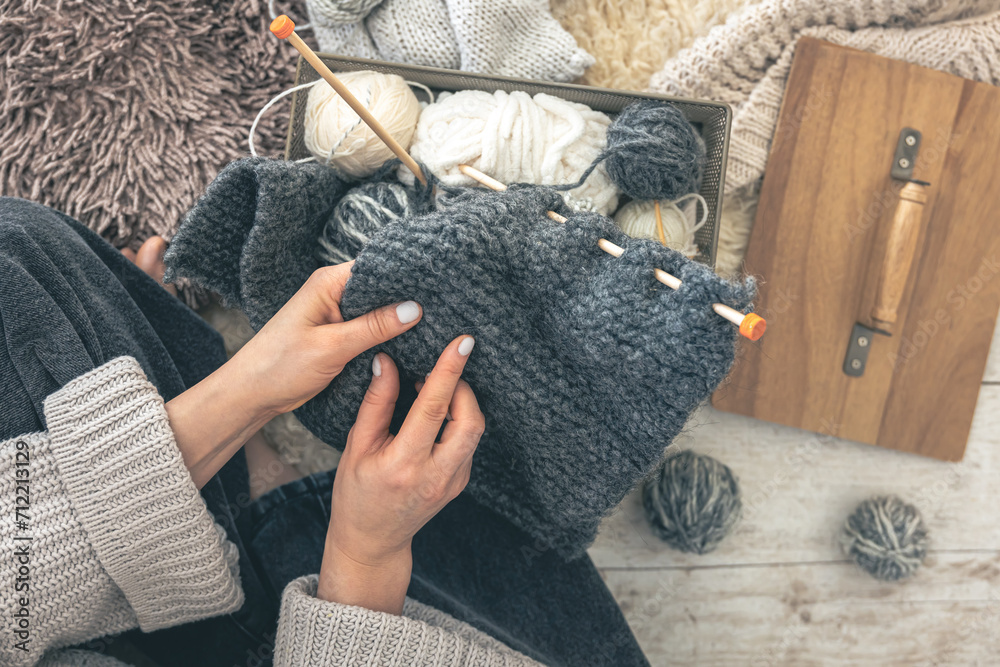Close-up of female hands knitting grey wool sweater, top view. Close-up of female hands knitting grey wool sweater, top view.