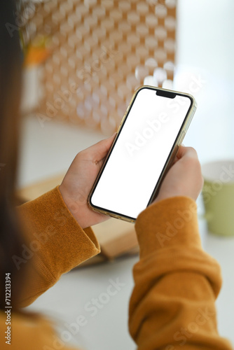 Woman in yellow sweater holding smartphone with empty screen. Closeup view