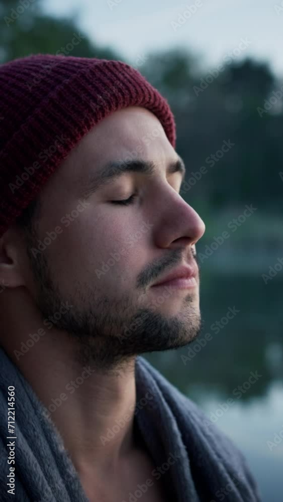 Concentrated man with towel at his shoulders standing at the lake shore and looking at the water Concentrated man with towel at his shoulders standing at the lake shore and looking at the water