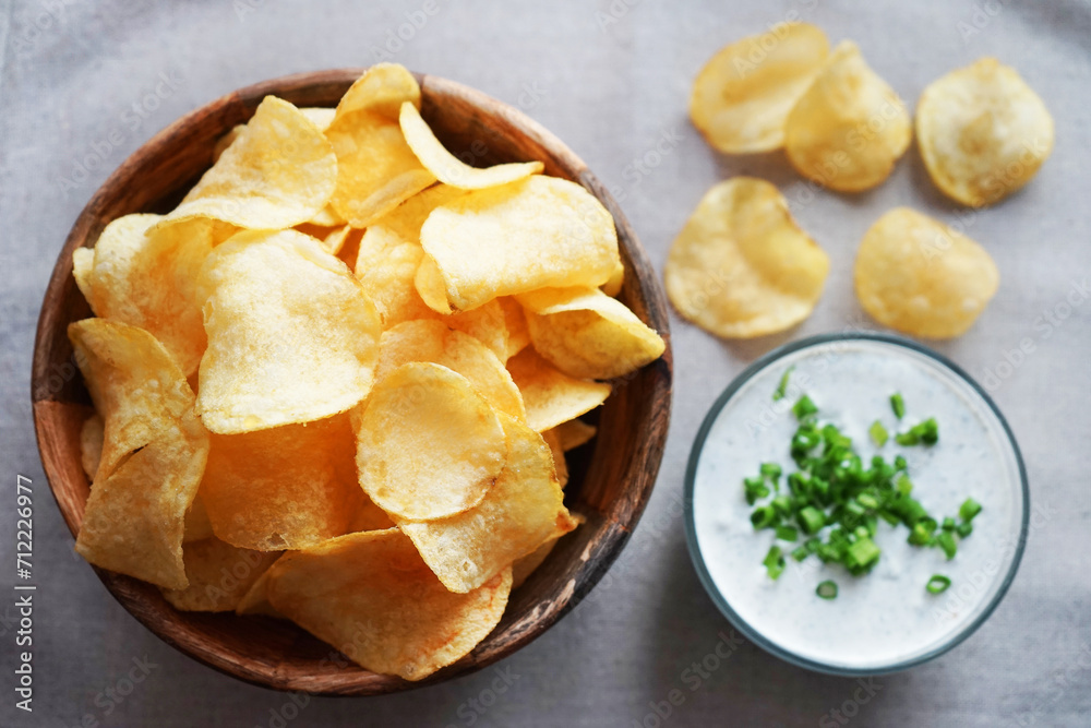 Potato chips with sauce with herbs on a gray background Potato chips with sauce with herbs on a gray background
