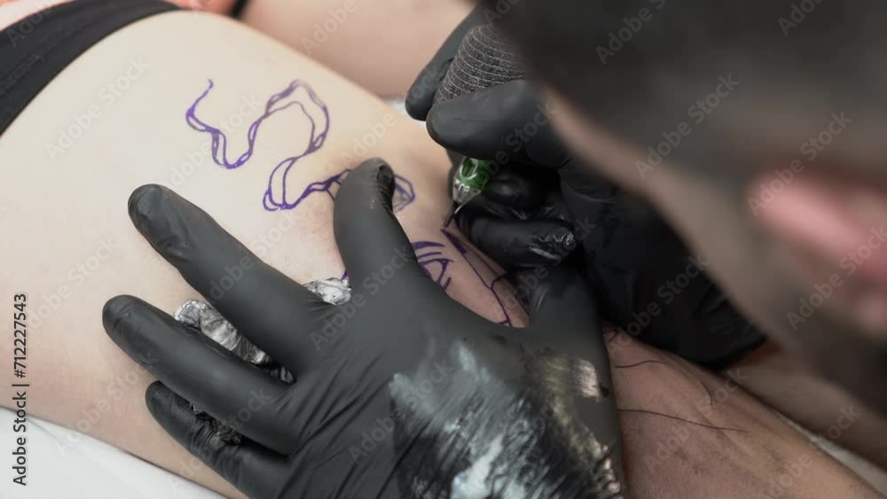 Plano detalle de tatuador realizando tatuaje