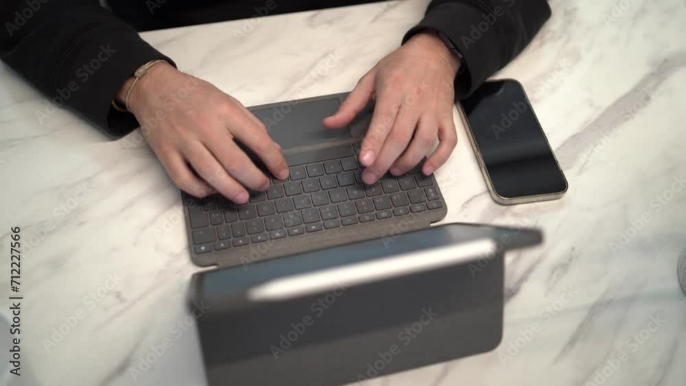 Toma en 4k de persona tecleando en un teclado de tablet en mesa de diseño