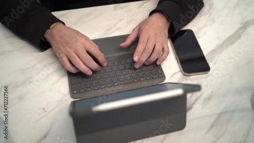 Toma en 4k de persona tecleando en un teclado de tablet en mesa de diseño photo